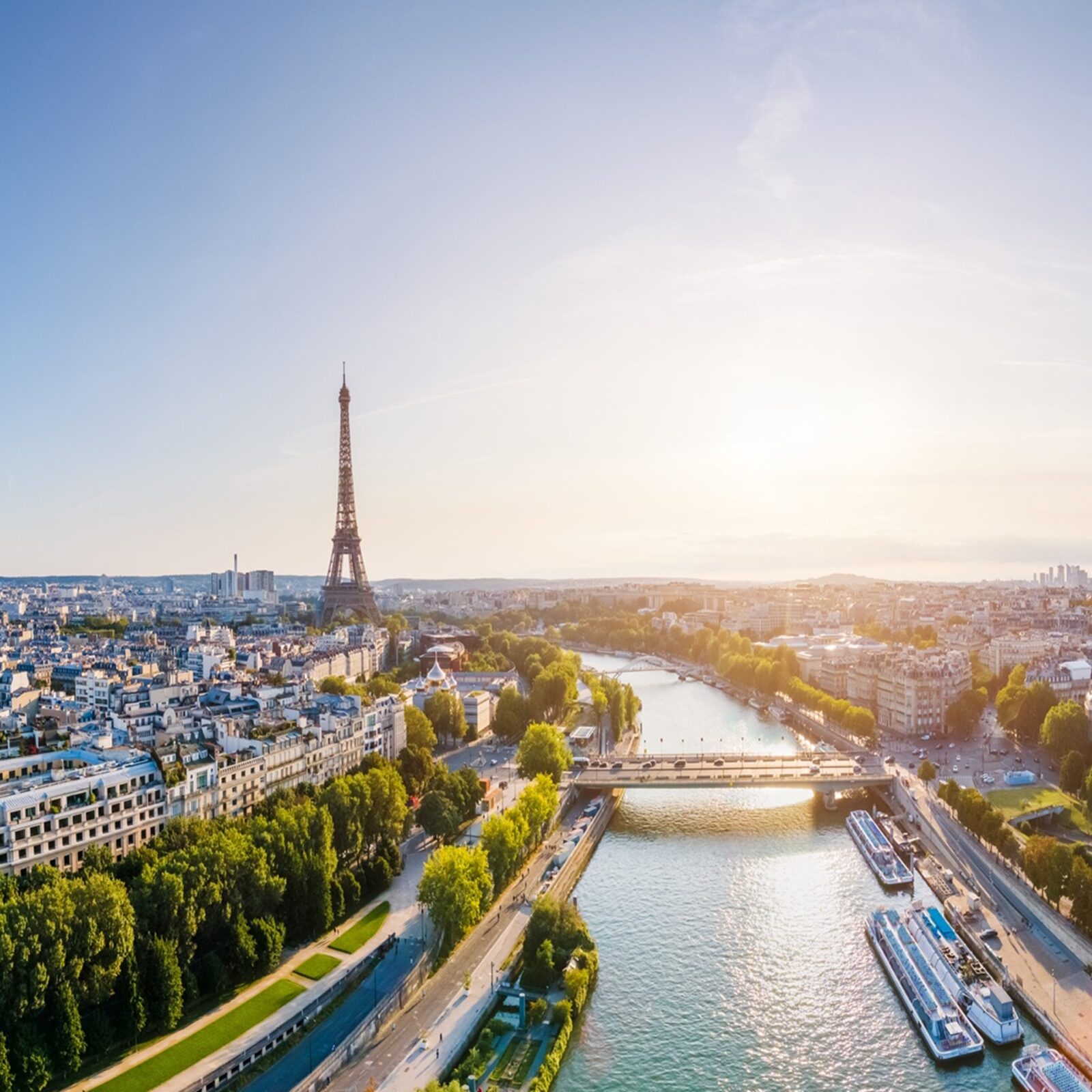 Paris aerial panorama with river Seine and Eiffel tower, France. Romantic summer holidays vacation destination. Panoramic view above historical Parisian buildings and landmarks with blue sky and sun